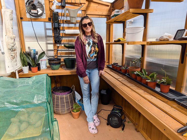 woman standing in a backyard discovery greenhouse