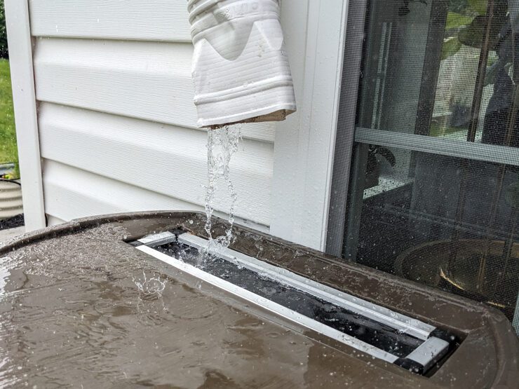water flowing from a gutter into a rain barrel