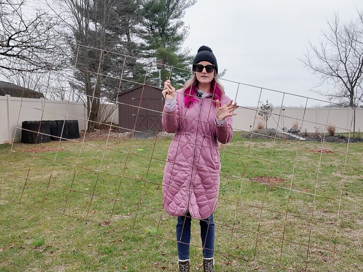woman holding a large wire fence panel